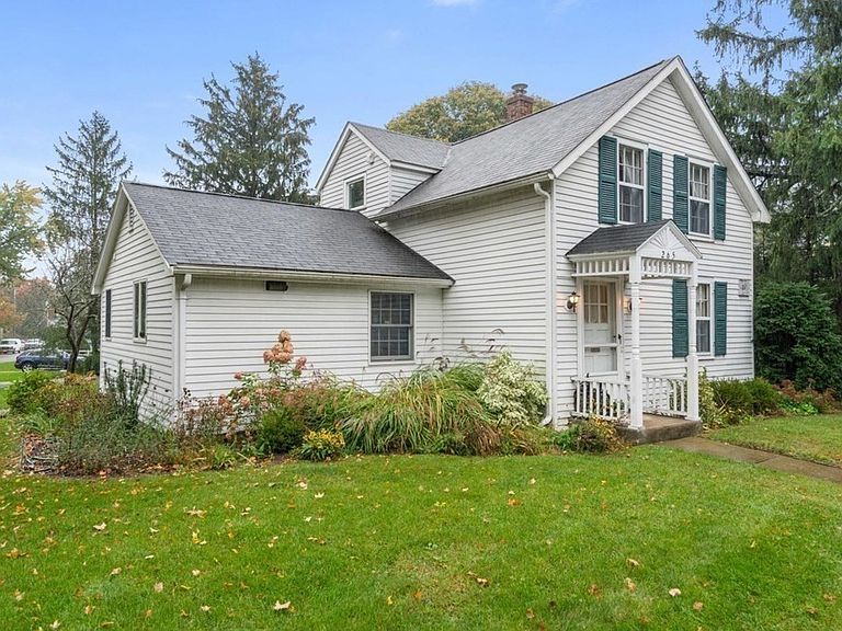 Small, New England home with white siding and a roof that needs replacing