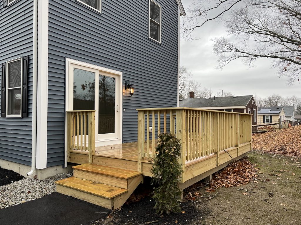 Blue home with pressure treated deck with 2 stairs and french doors leading inside